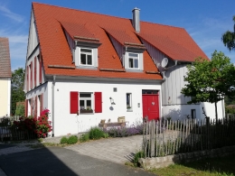 Abgebildet ist die Eingangsseite (Ostseite) und ein Teil der Hofseite (Süden). Wichtig für uns war eine Eingangstüre mit einer Öffnung 2/3 (Haupttüre) und 1/3 feststehend, kann aber optional geöffnet werden. Der halbrunde Treppenaufgang mit Holzverschalung war aufgrund der räumlichen Aufteilung innen eine tolle Idee meiner Frau. 
Auch die Gauben waren unser Wunsch an Georg Schilling, damit der fränkische Baustil erkennbar wird.